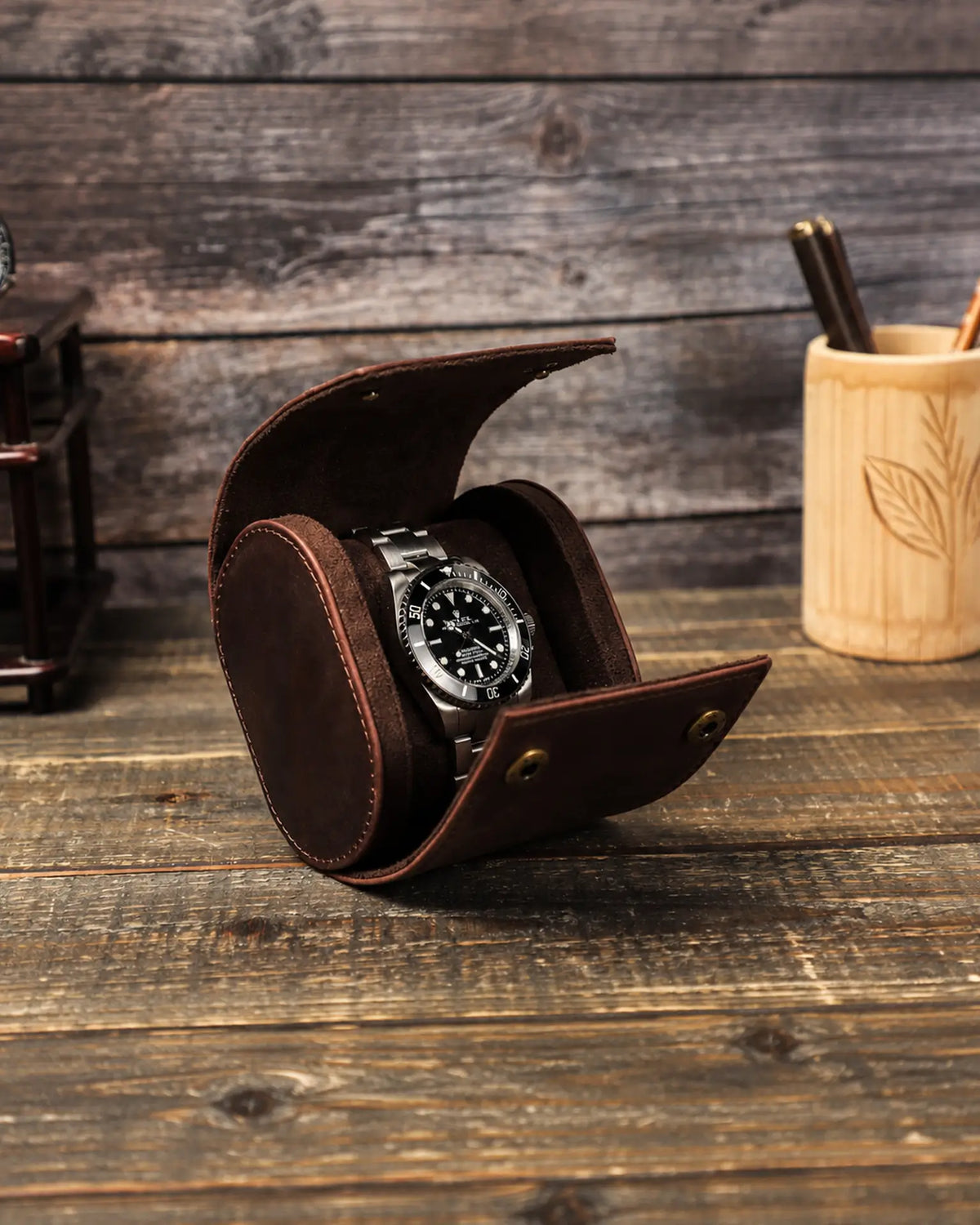 Side view of the open watch roll with a watch on the cushion and the front snap fasteners exposed.