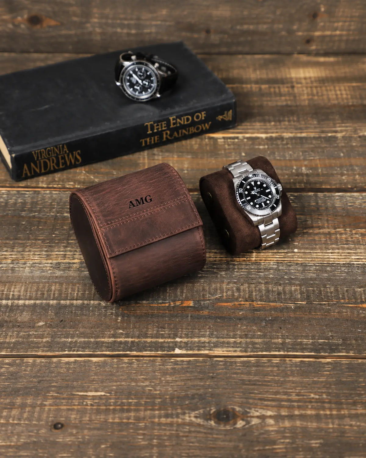 Brown leather watch roll with an AMG monogram on the front flap, beside a watch on its cushion. Personalization example.