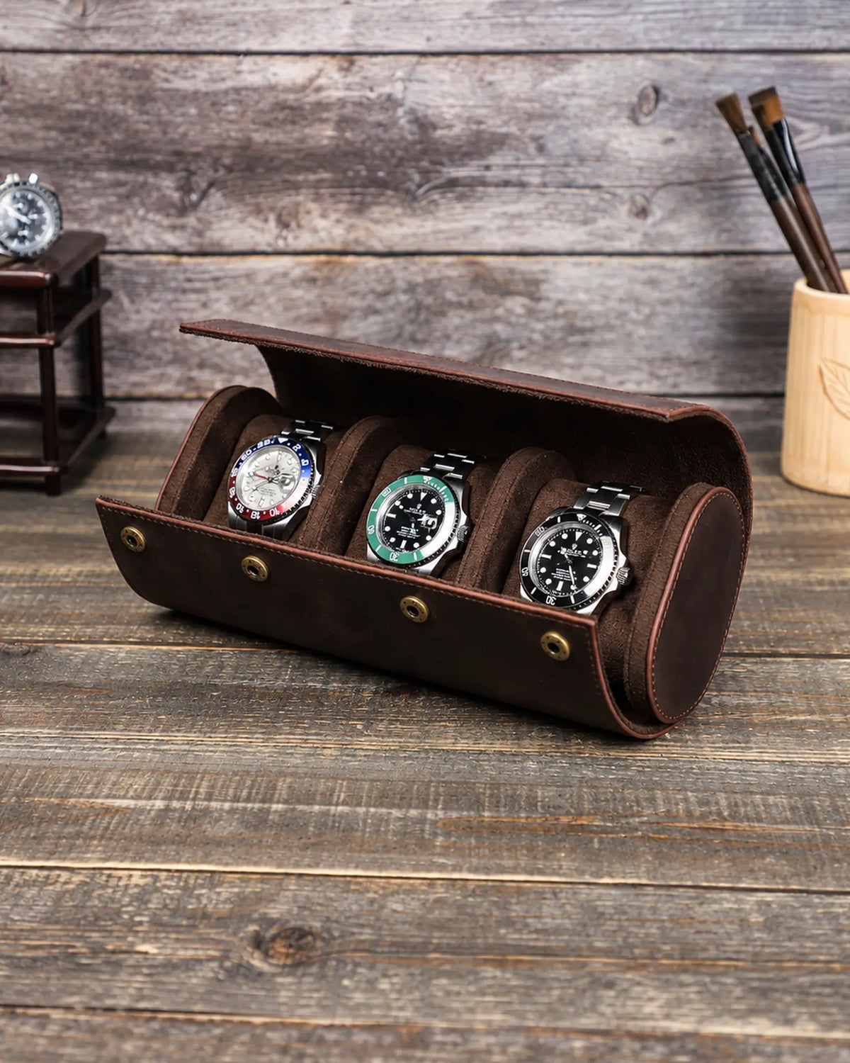 Espresso triple watch roll open on a wooden table with three watches on individual cushions.
