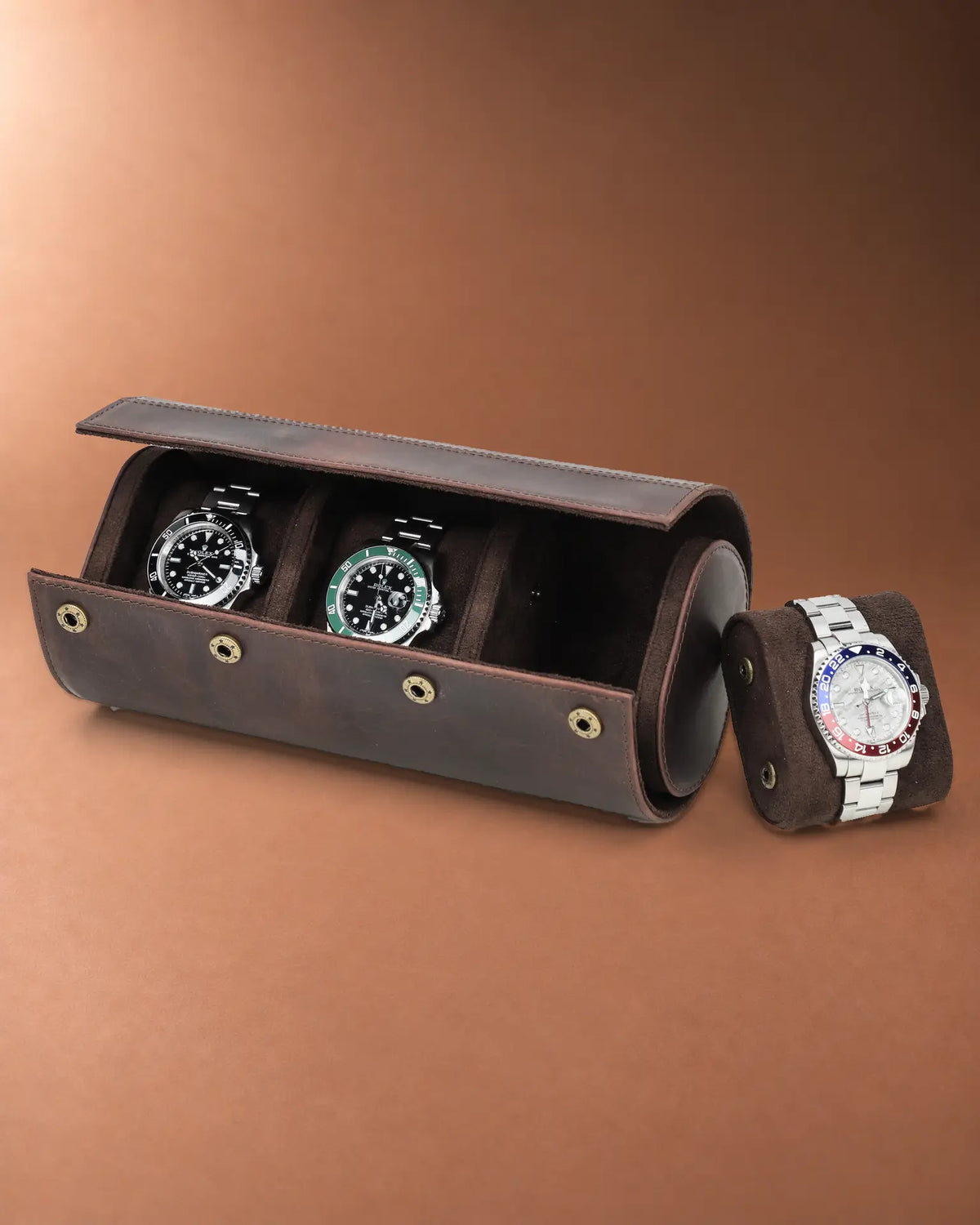 Open triple watch roll with two watches inside and a third watch on a removable cushion beside it.