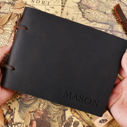 Black leather notebook with 'MASON' embossed on it, held over an old map.