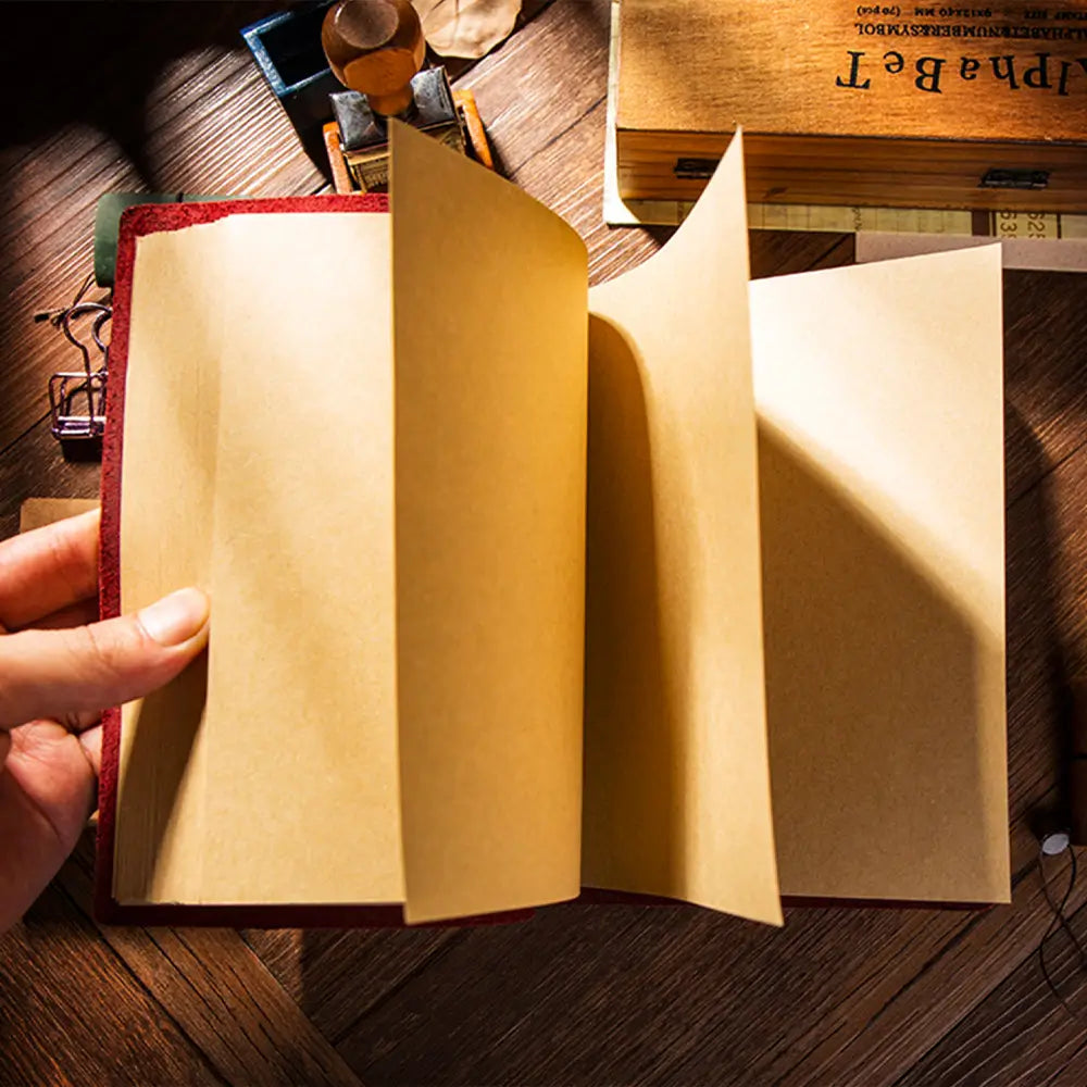 Hand holding a leather-bound book with a wooden surface in the background