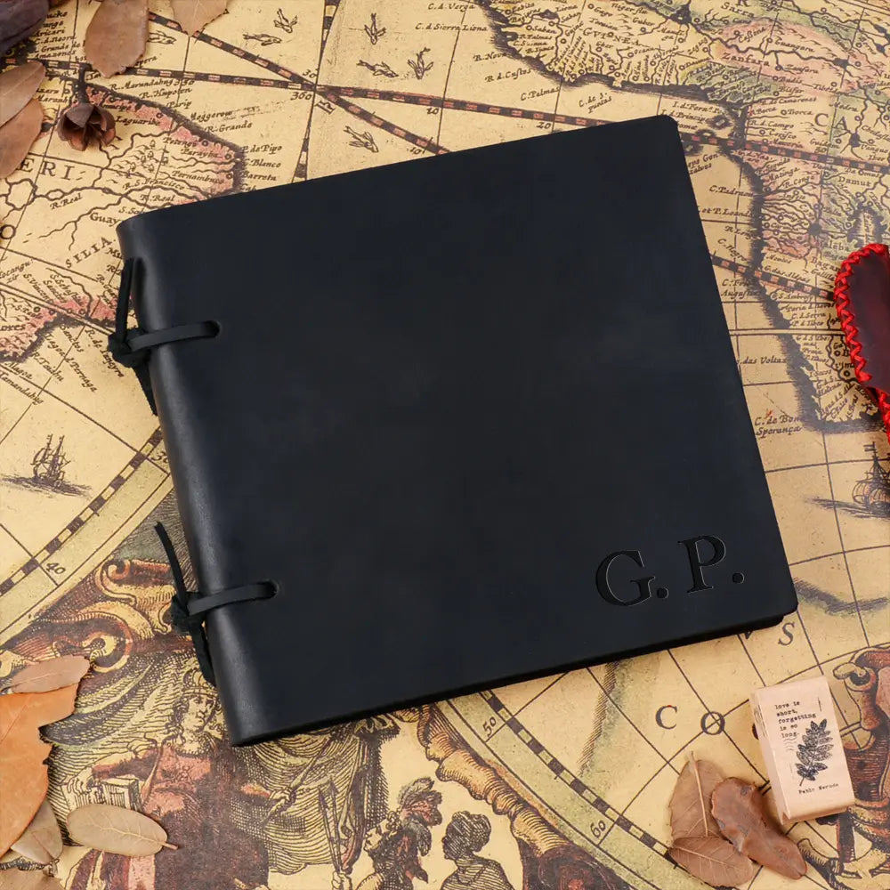 Black leather notebook with 'G.P.' embossed on it, placed on an old map.