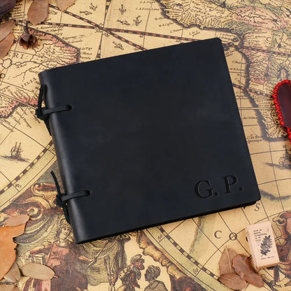 Black leather notebook with 'G.P.' embossed on it, placed on an old map.