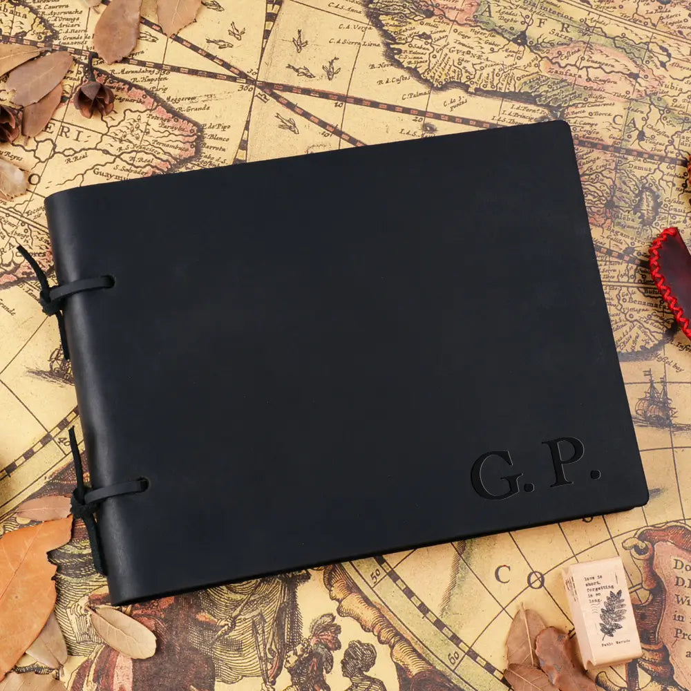 Black leather notebook with 'G.P.' embossed on it, placed on an old map.