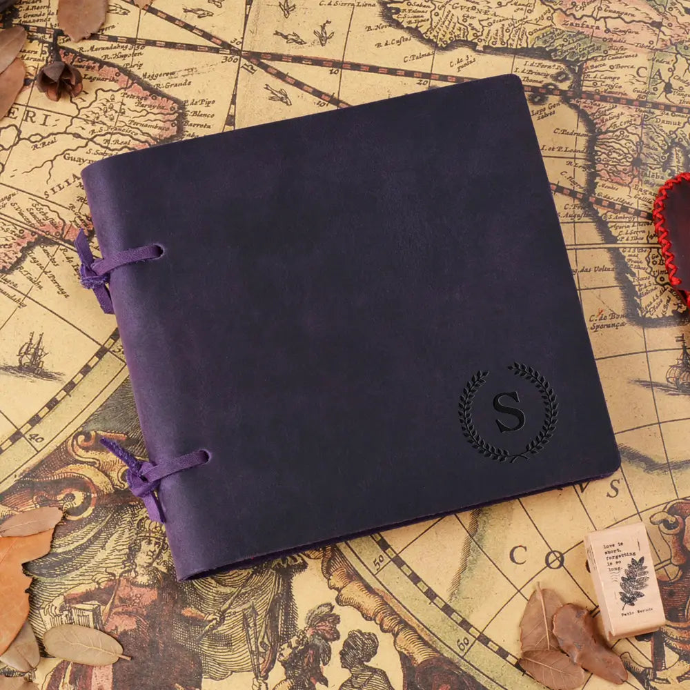 Purple leather notebook with a monogram on an old world map