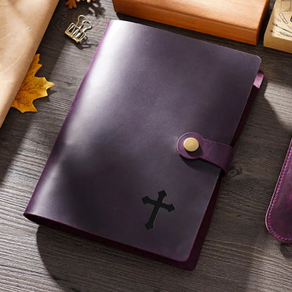 Purple leather notebook with a cross emblem on a wooden surface