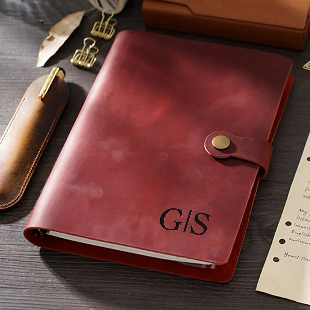 Red leather notebook with 'GIS' initials on a wooden surface