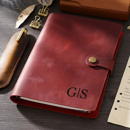 Red leather notebook with 'GIS' initials on a wooden surface