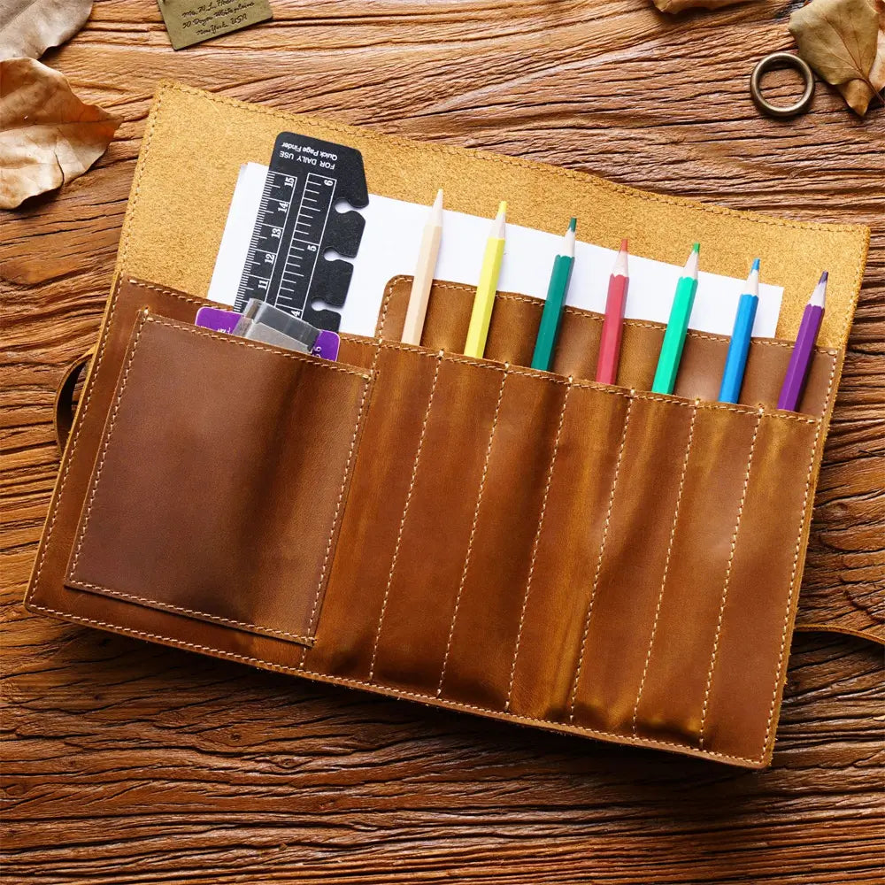 Brown leather pen case with colorful pencils on a wooden surface