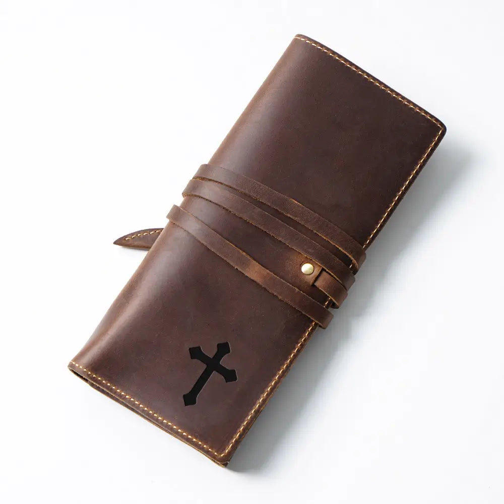 Brown leather pen case with a black cross emblem on a white background