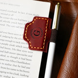 The red square bookmark is sandwiched with a white pen on the book.