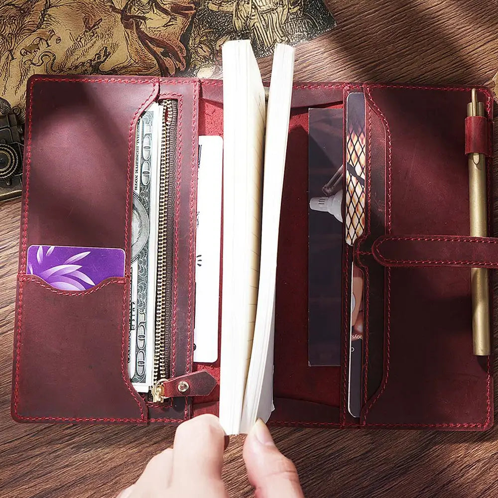 Person writing in personalized leather journal on wooden desk
